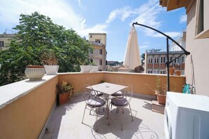 A rooftop terrace with a table and chairs, potted plants, and a washing machine.