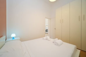 A hotel room with a bed, a nightstand with a lamp, and a wardrobe.