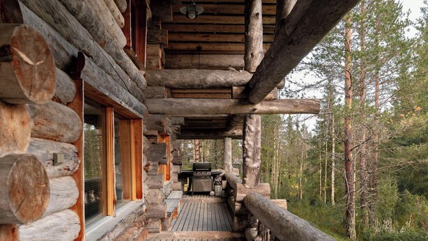 A log cabin with a wooden deck, a grill, and a view of the forest. - Villa Mörri - Cozy 4BR Cabin in Ruka (Kuusamo)