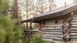 A log cabin with a wooden ladder leading to a door, surrounded by tall trees. - Villa Mörri - Cozy 4BR Cabin in Ruka (Kuusamo)