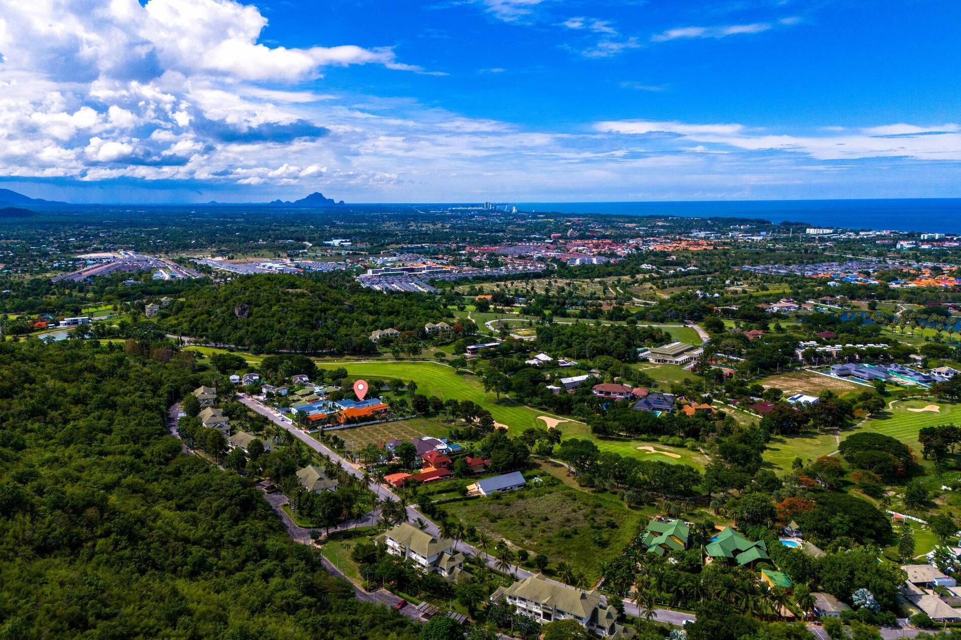 An aerial view of a residential area with houses, roads, and a large body of water in the background.