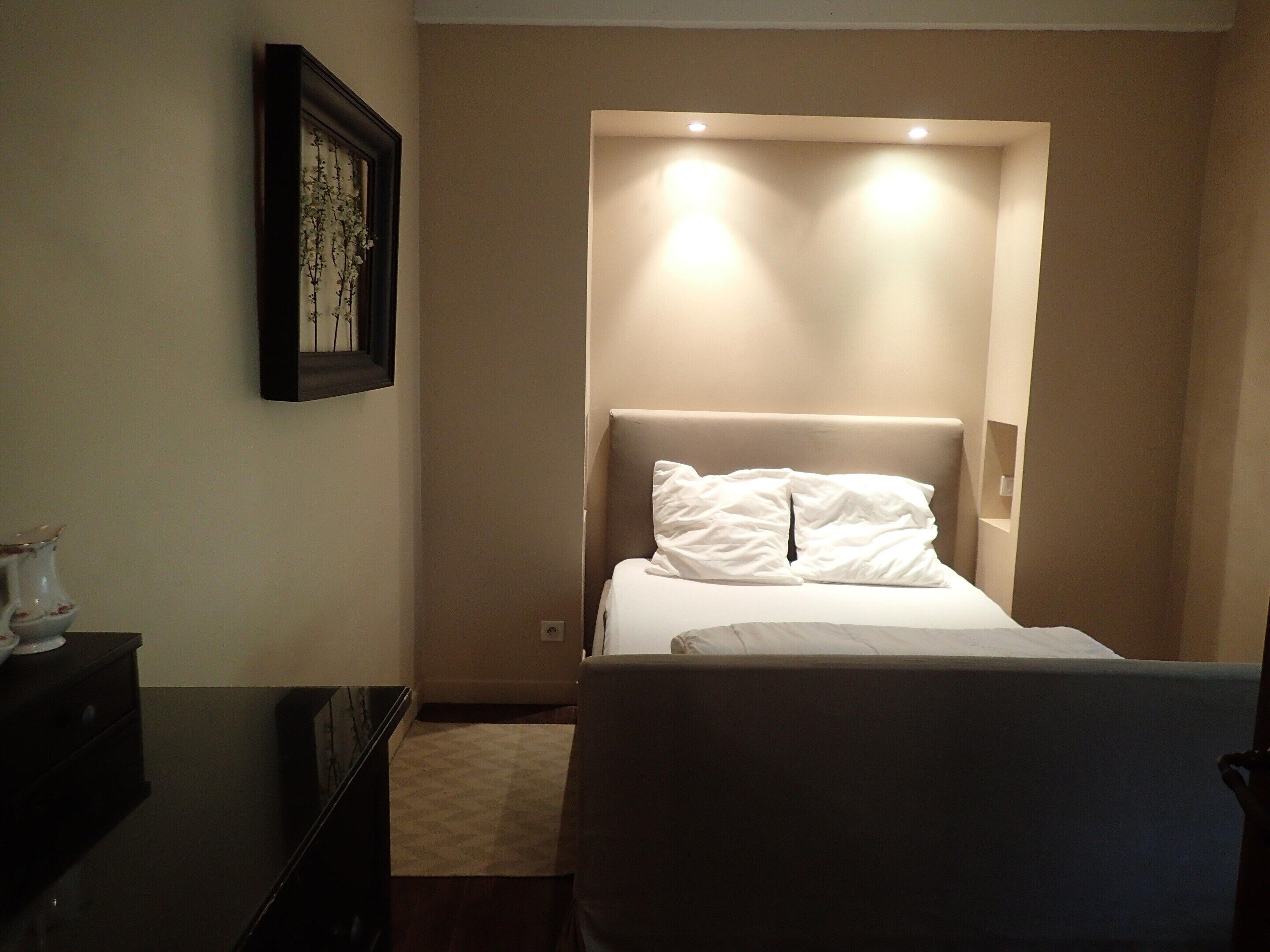 A hotel room with a bed, a dresser, and a framed picture on the wall.