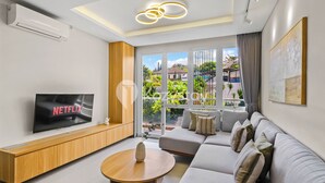 Una sala de estar moderna con televisor de pantalla plana, mueble de entretenimiento de madera y un sofá gris.