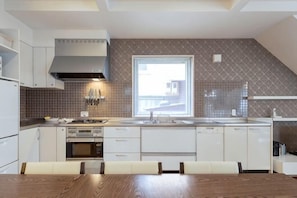 A modern kitchen with white cabinetry, a built-in oven, and a window providing natural light.