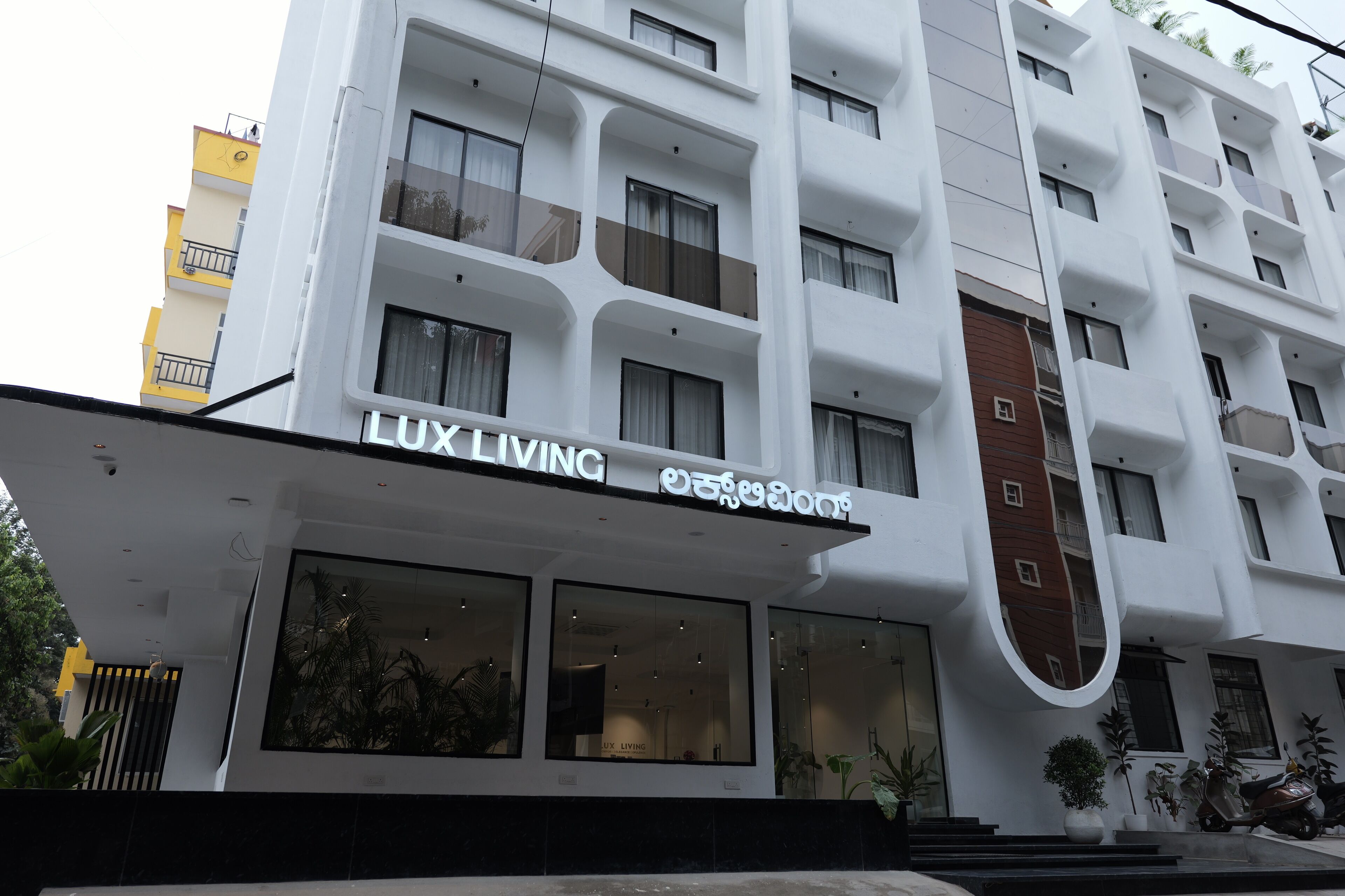 Un immeuble à plusieurs étages, sur lequel on peut lire l’inscription « LUX LIVING », et qui présente un design architectural moderne.