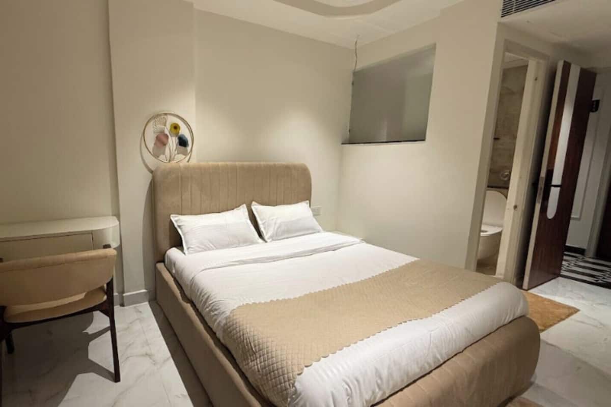 Un dormitorio con cama, una silla, una mesita de noche y un espejo.