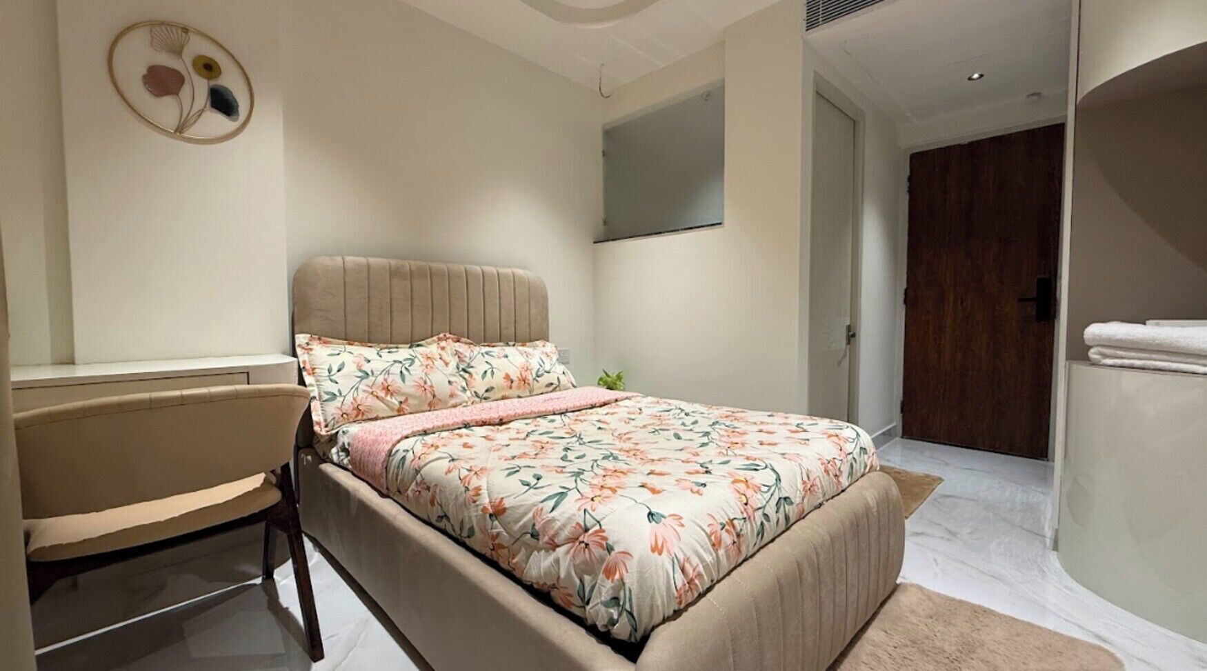 Een slaapkamer met een bed, een stoel, een wanddecoratie en een deur.