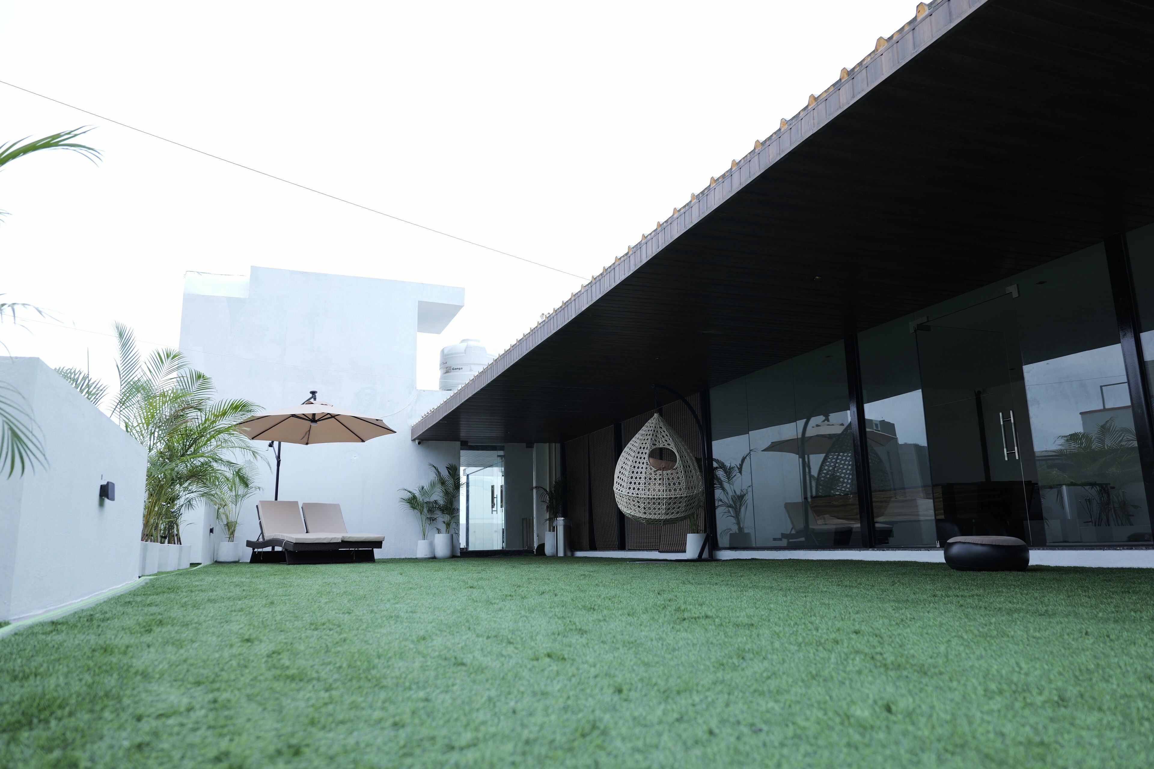 Une maison moderne dotée d’un patio couvert, d’un fauteuil suspendu et d’une pelouse.