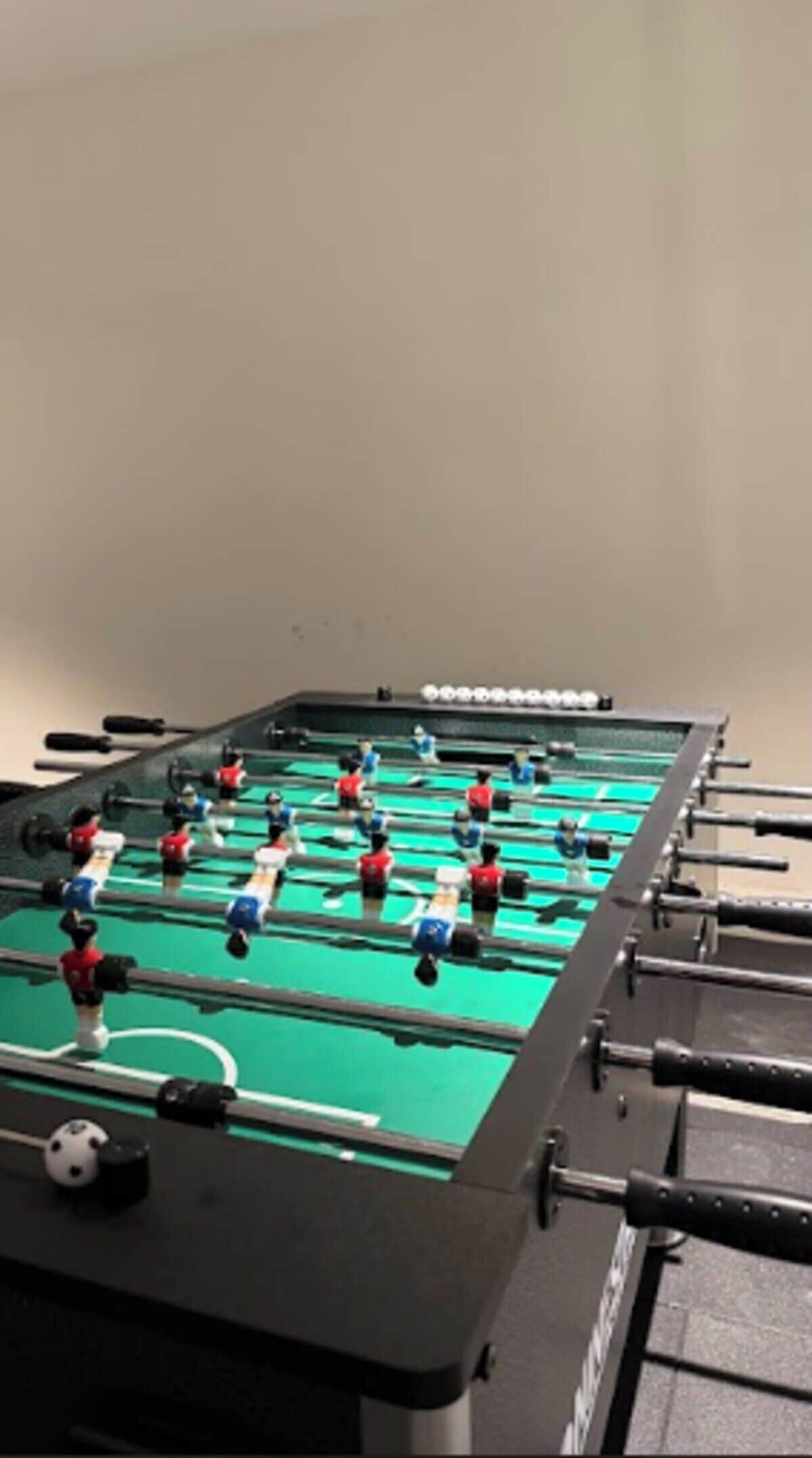 A foosball table with multiple players in red and blue uniforms.