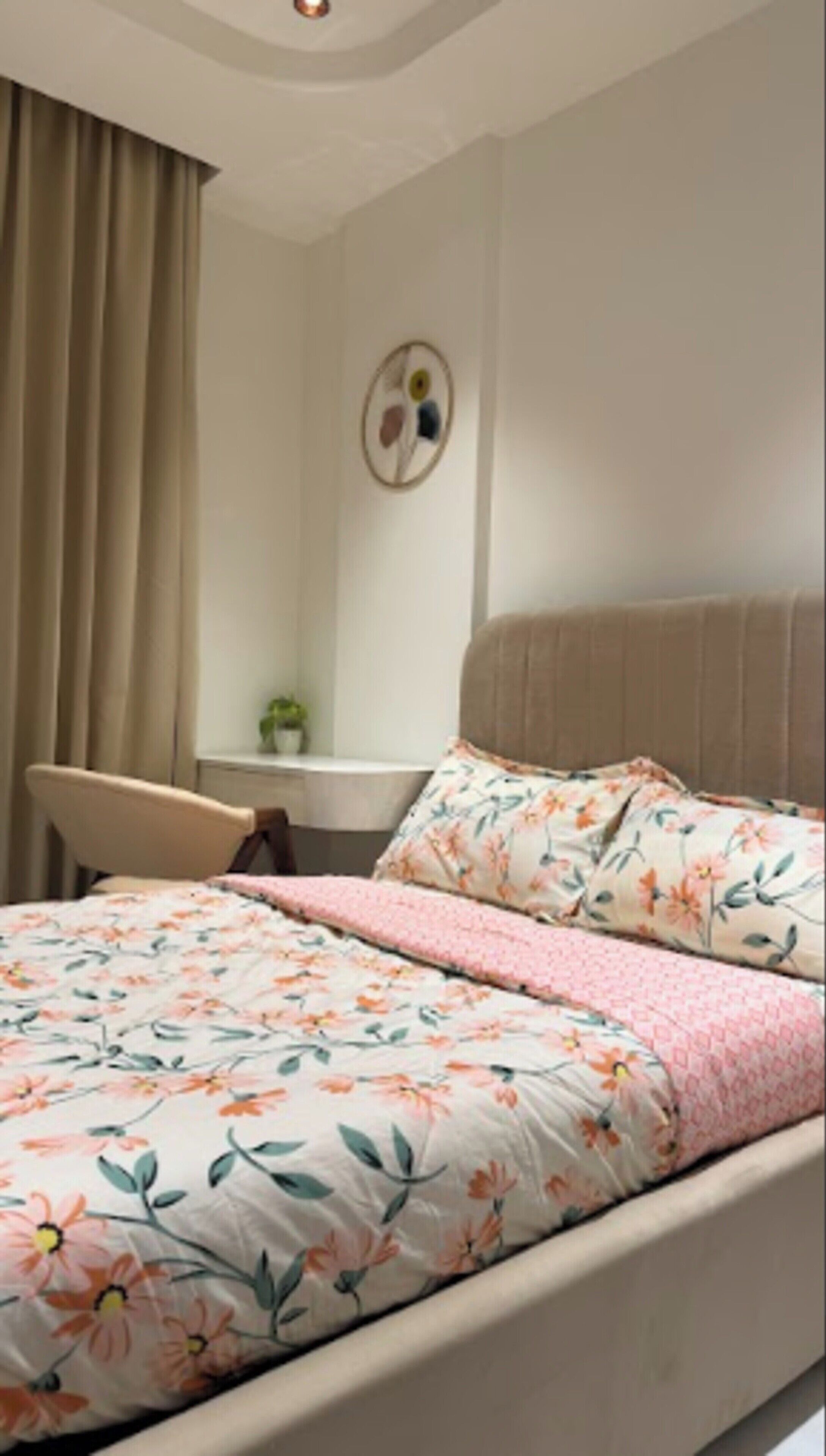 A bedroom with a bed, a chair, a desk, and a wall decoration.