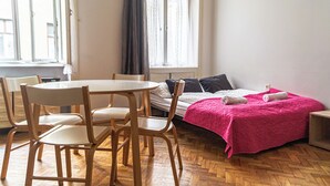 Um quarto com uma cama, uma mesa com cadeiras e uma janela com cortinas.