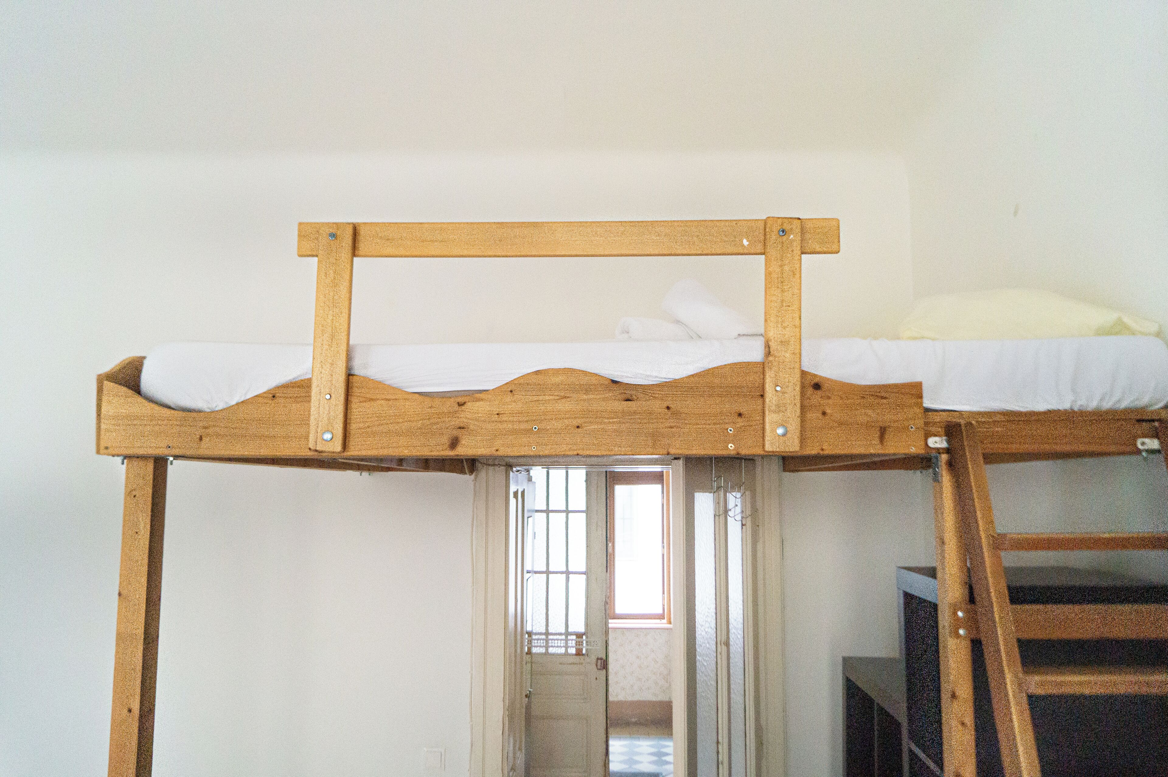 Ein Stockbett mit Holzbettrahmen, weißer Bettwäsche und einer Treppe.