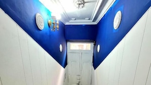 A narrow hallway with blue and white walls, a wooden handrail, and a white door at the end. - Blue hostel (Buenos Aires)