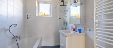 A modern bathroom with a bathtub, a shower, and a sink.