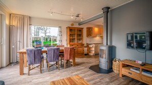 A modern kitchen with wooden cabinets, a built-in stove, and a dining area with a wooden table and chairs. - Modernly Furnished 6-person Bungalow in the Seaside Resort of De Koog (De Koog)