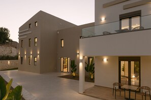 A modern two-story building with a balcony, large windows, and outdoor seating area. - Anassa Villa, with 110m² Pool & Emerald Gardens (Rethymno)