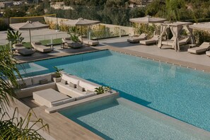 A pool area with multiple lounge chairs and umbrellas, surrounded by a fence and greenery. - Anassa Villa, with 110m² Pool & Emerald Gardens (Rethymno)