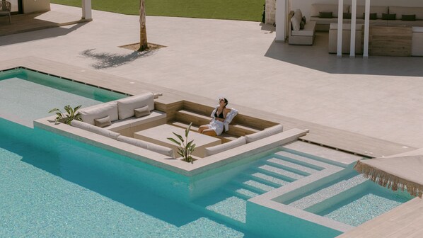 A poolside area with a sun lounger and a small seating area. - Anassa Villa, with 110m² Pool & Emerald Gardens (Rethymno)