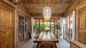 A wooden dining room with a large table, chairs, and a hanging light fixture. - Desa La Casa Modular (Ubud)