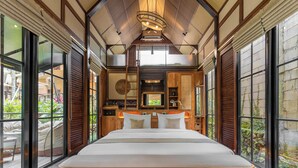 A spacious bedroom with a large bed, wooden headboard, and a view of the garden through large windows. - Desa La Casa Modular (Ubud)