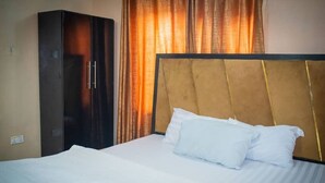 A hotel room with a bed, a wardrobe, and curtains. - PROMISE HOTELS HOMES AND APARTMENT (Lagos)