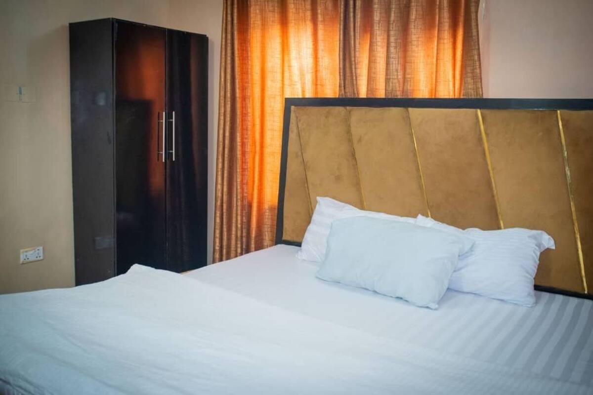 A hotel room with a bed, a wardrobe, and curtains.