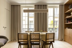 Un comedor con una mesa redonda, cuatro sillas y un ventanal con cortinas.