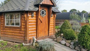 A log cabin with a chimney, a window, and a door with a decorative glass panel. - 5 Star Holiday Home in Haderslev (Haderslev)