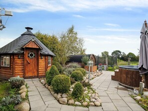 A wooden cabin with a hexagonal window, a stone pathway, and a hot tub. - 5 Star Holiday Home in Haderslev (Haderslev)