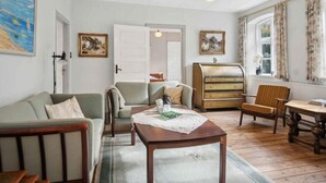A cozy living room with a sofa, armchairs, a wooden coffee table, and a vintage dresser. - 5 Star Holiday Home in Haderslev (Haderslev)