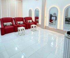 A modern lounge area with red sofas and small tables, a large mirror, and a clean, tiled floor.