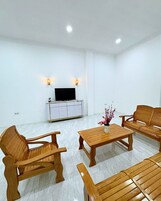 A modern living room with wooden furniture, a flat-screen TV, and decorative wall sconces.