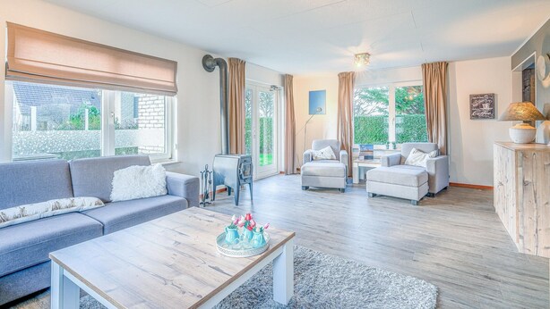 A spacious living room with a sofa, armchairs, a coffee table, and a fireplace. - Charming Villa With Wood Stove Near the sea and Forest (De Koog)