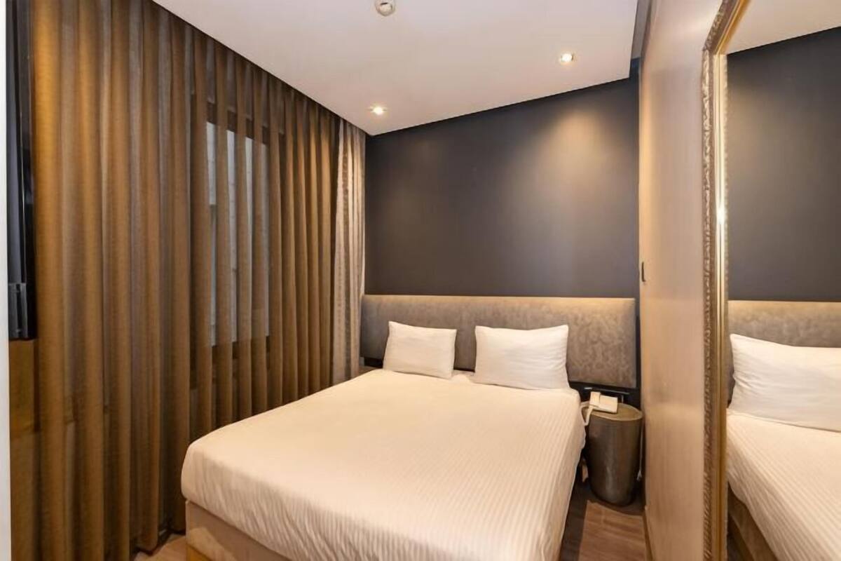 Una habitación de hotel moderna con una cama grande, un panel de pared de madera y una pared de acento oscura.