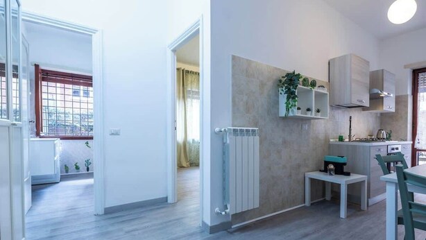 A modern kitchen with a built-in stove, a small dining table, and a radiator. - BuddyRent - Garden House - Vaticano - 3 ospiti (Roma)