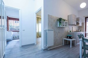 A modern kitchen with a built-in stove, a small dining table, and a radiator. - BuddyRent - Garden House - Vaticano - 3 ospiti (Roma)