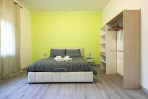 A bedroom with a bed, a bedside table, a wardrobe, and a window with curtains. - BuddyRent - Garden House - Vaticano - 3 ospiti (Roma)