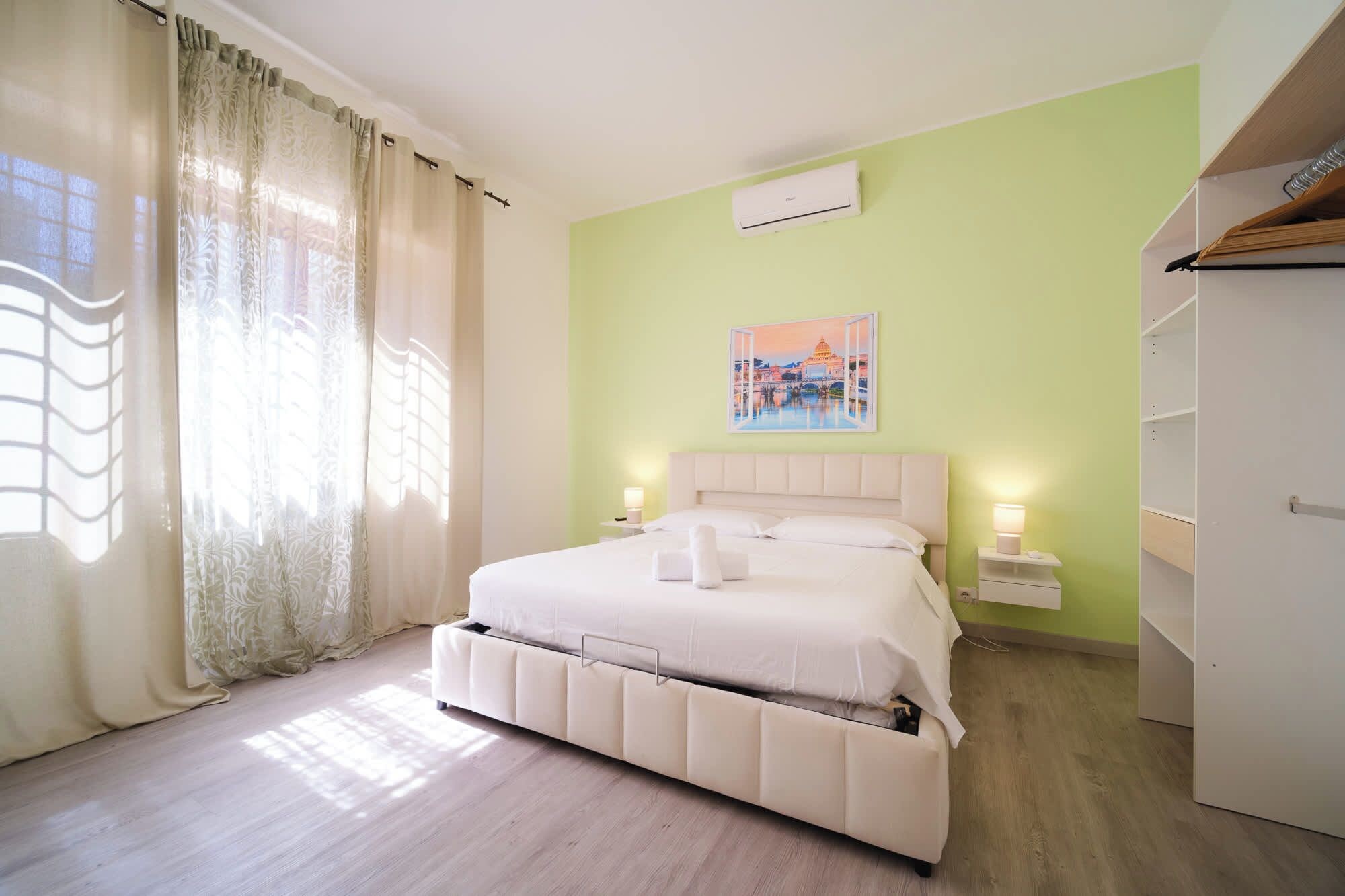 A hotel room with a bed, a nightstand, a wall-mounted air conditioner, and a wardrobe.