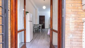 A hallway with a wooden door frame, a refrigerator, a table with chairs, and a door in the background. - BuddyRent - Garden House - Vaticano - 3 ospiti (Roma)