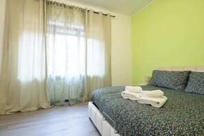 Een slaapkamer met een bed, gordijnen en een groene wand.