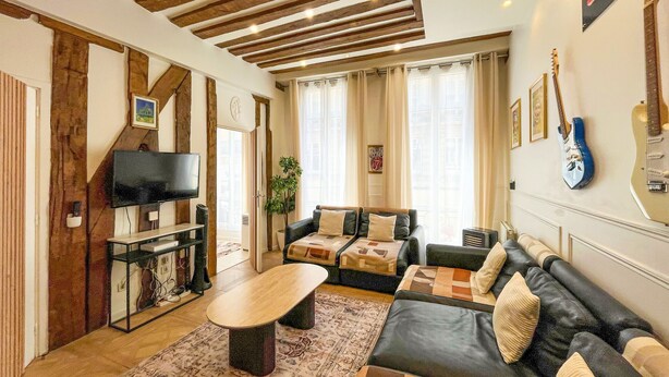 Ein Wohnzimmer mit einer Couch, einem Couchtisch, einem Fernseher und Gitarren an der Wand.