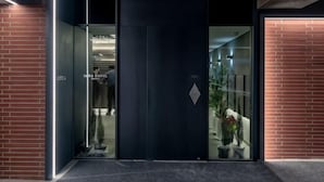 A modern building entrance with glass doors, a visible interior hallway, and a potted plant. - Hotel Tara (Seoul)