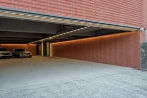A covered parking garage with a brick wall and a concrete floor. - Hotel Tara (Seoul)
