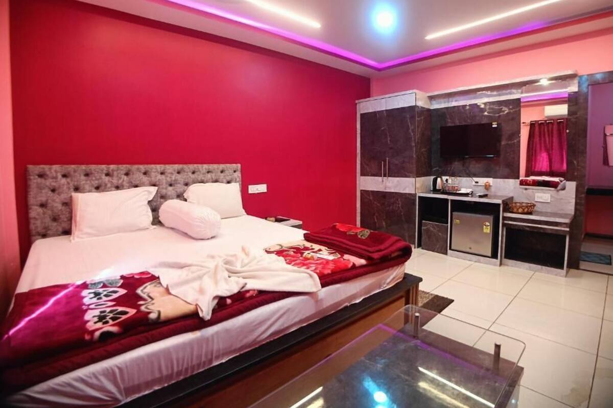A modern bedroom with a large bed, a vanity with a mirror, and a television.