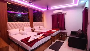 A hotel room with two beds, a sofa, and a small table. - CHUTI BEACH REOSORT (Mandarmani)