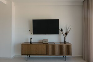 Un saló modern amb un mestre gegant de fusta, un televisor de pantalla plana, un ram de flors decoratiu i un llibre.
