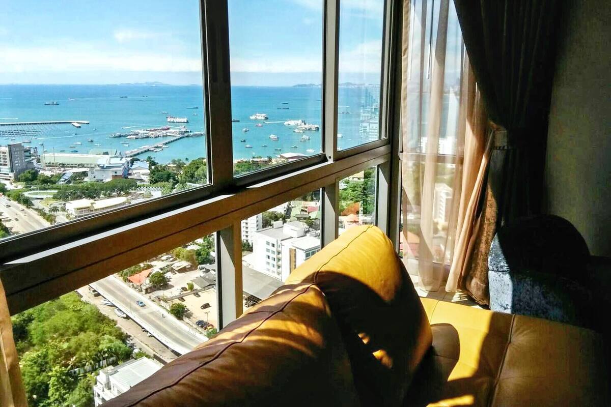 A room with a large window overlooking a marina and cityscape.