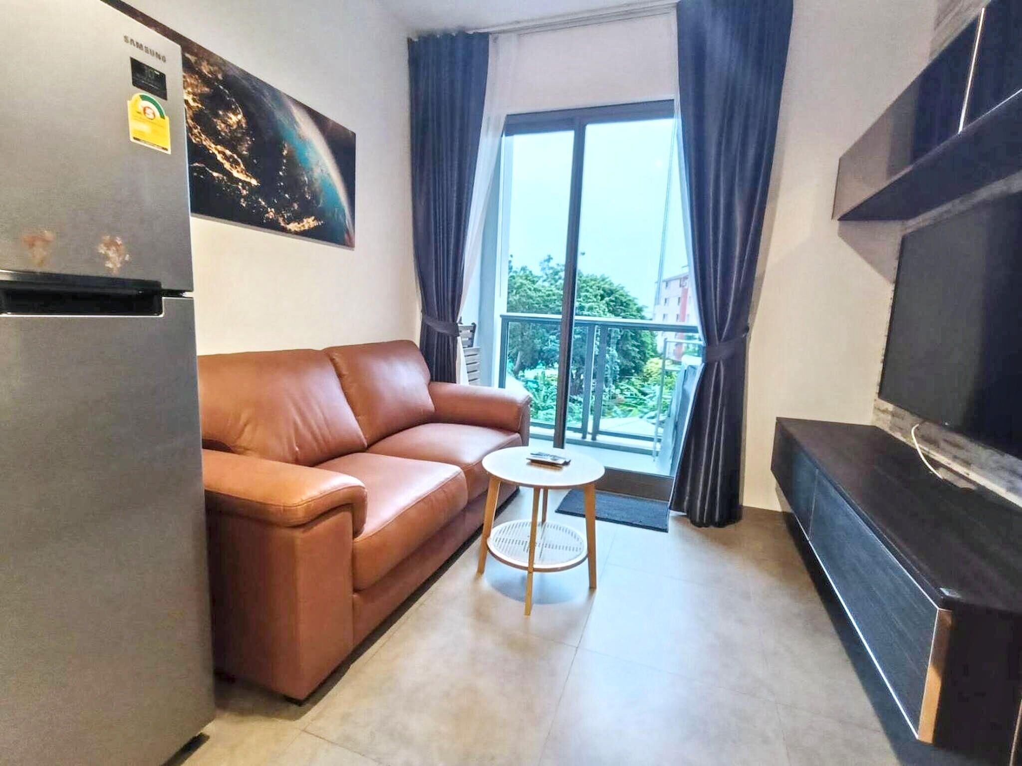 Una sala de estar con un sofá, una mesita, un televisor y un refrigerador.