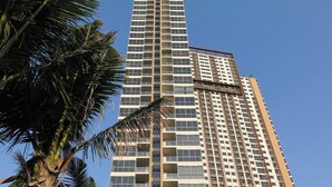 A tall, modern high-rise building with multiple floors and balconies, surrounded by palm trees. - The Unixx South Pattaya (Pattaya)