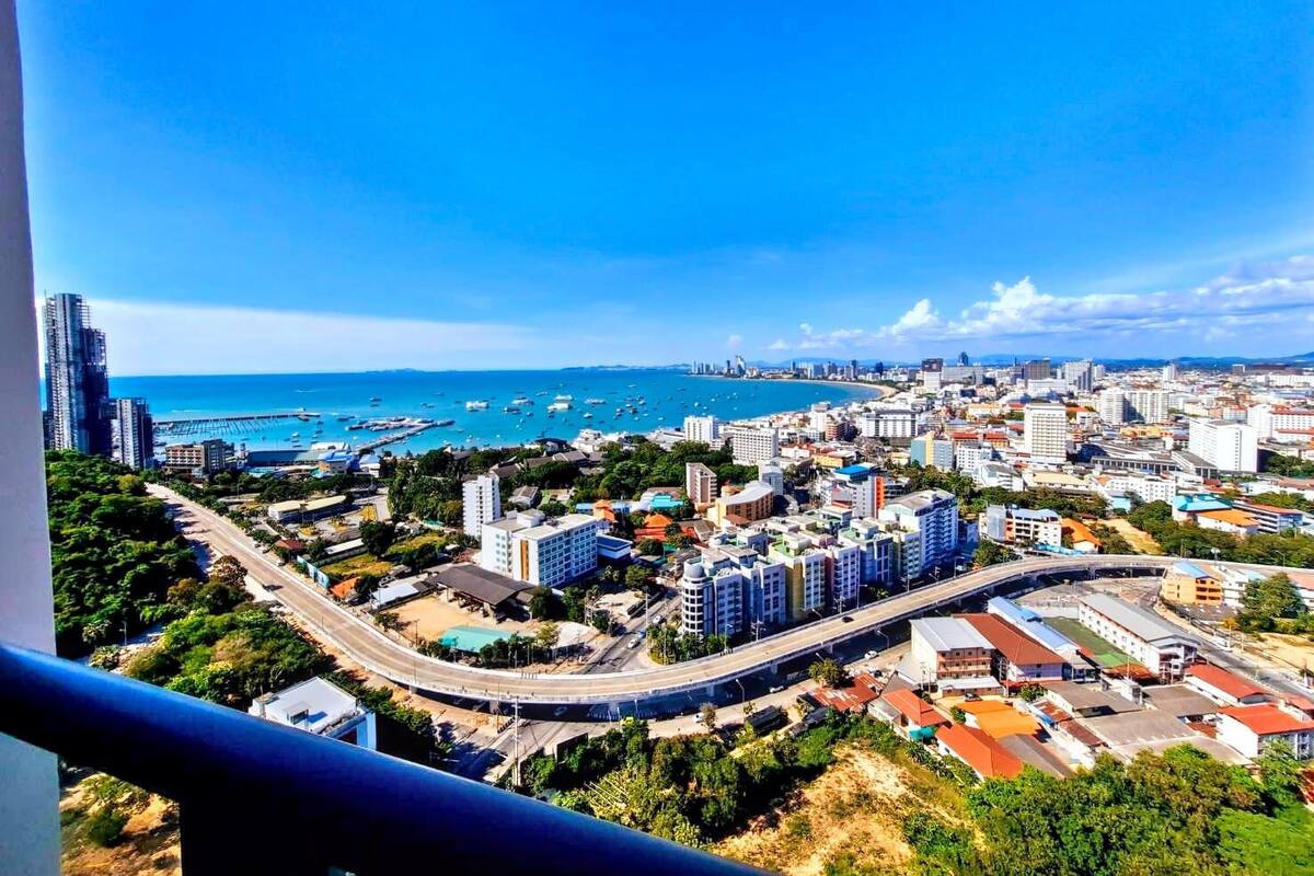 A coastal cityscape with a prominent highway, buildings, and a marina.